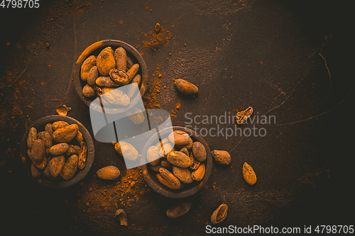 Image of Organic cocoa beans in small bowls on brown background