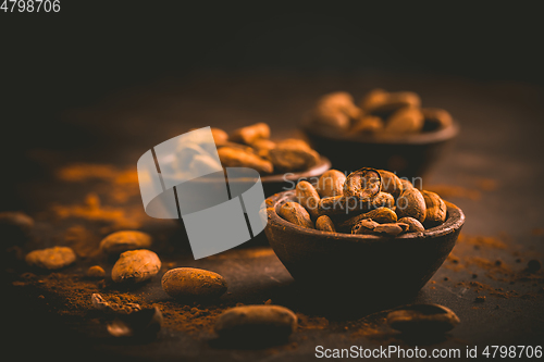 Image of Organic cocoa beans in small bowls on brown background