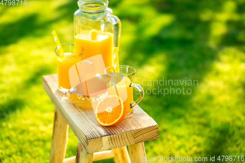 Image of Two glasses of tasty freshly squeezed orange juice on garden stool