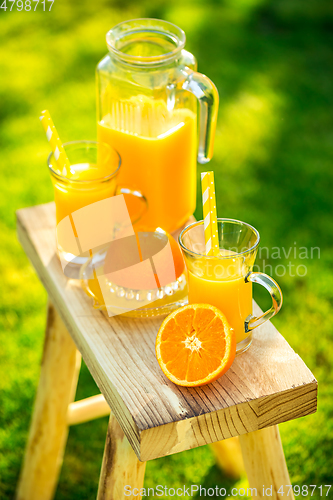 Image of Two glasses of tasty freshly squeezed orange juice on garden stool