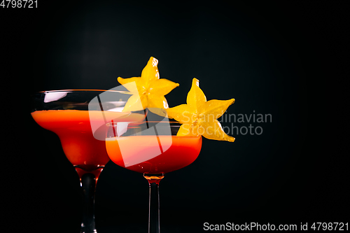 Image of Red cocktail decorated with starfruit on black background