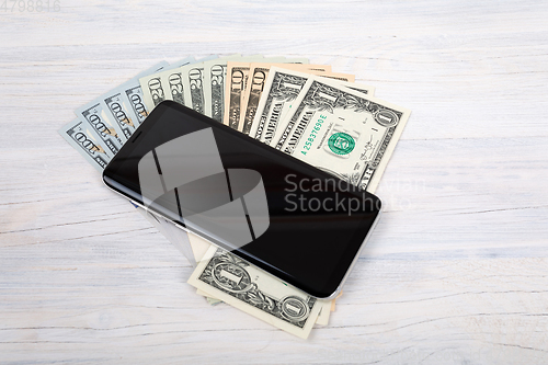 Image of cellular phone and American dollar money on white