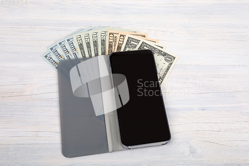 Image of cellular phone and American dollar money on white