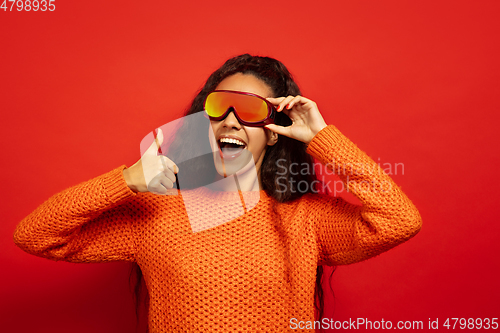 Image of African-american young woman\'s portrait in ski mask on red background