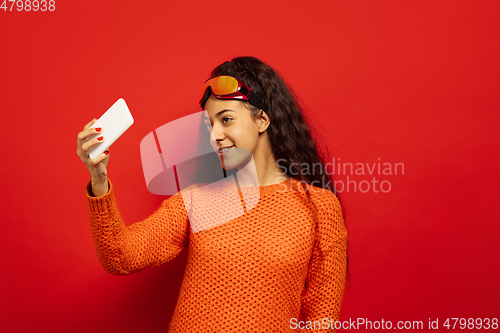 Image of African-american young woman\'s portrait in ski mask on red background