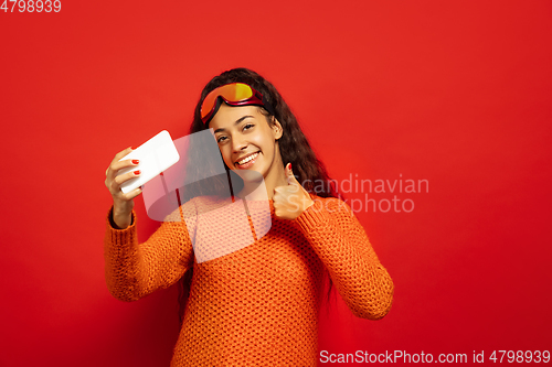 Image of African-american young woman\'s portrait in ski mask on red background