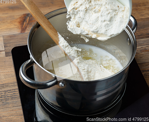 Image of flour is poured into a pot with hot water and butter