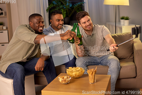 Image of male friends with smartphone taking selfie at home