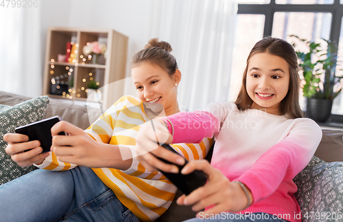 Image of girls and playing game on smartphones at home
