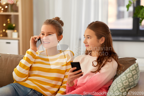 Image of happy teenage girls with smartphones at home