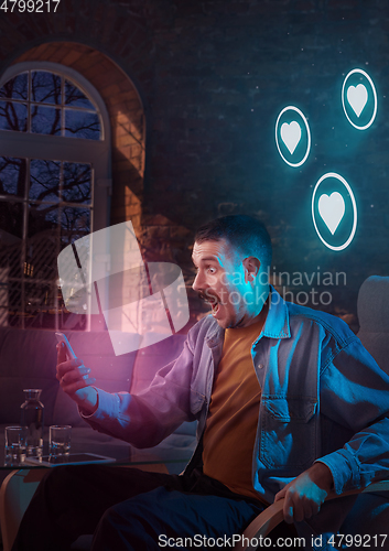 Image of Man using gadget and receive neon notifications at home at night