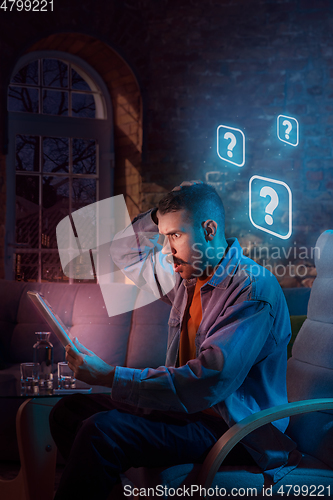 Image of Man using gadget and receive neon notifications at home at night