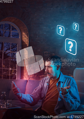 Image of Man using gadget and receive neon notifications at home at night