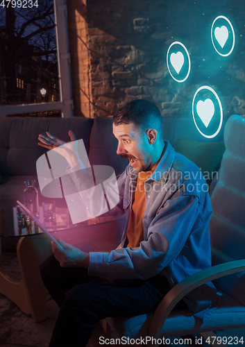 Image of Man using gadget and receive neon notifications at home at night