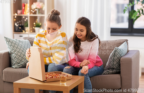 Image of happy teenage girls eating takeaway pizza at home