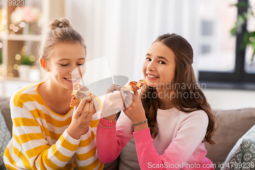 Image of happy teenage girls eating pizza at home