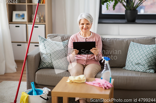 Image of senior woman using tablet pc after cleaning home