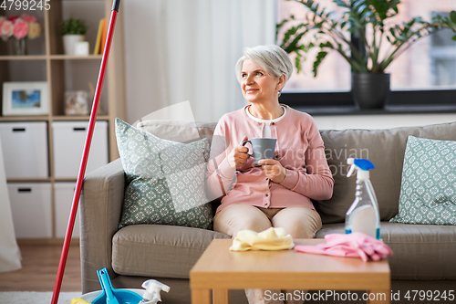 Image of senior woman drinking coffee after home cleaning