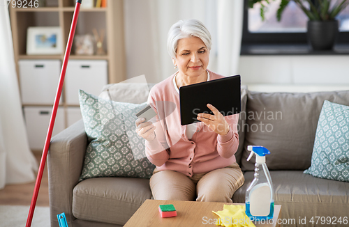 Image of old woman with tablet pc and credit card at home