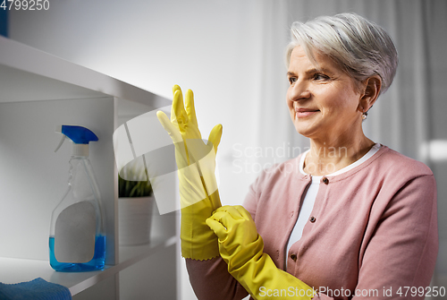 Image of senior woman putting protective rubber gloves on