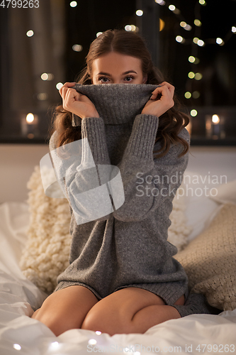 Image of young woman in woolen sweater at home at night