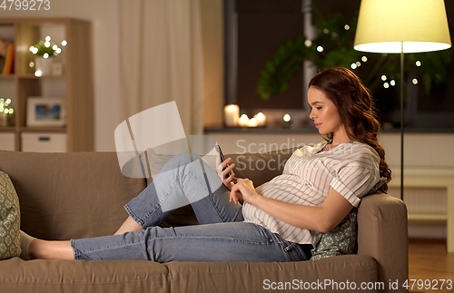 Image of happy pregnant woman with smartphone at home