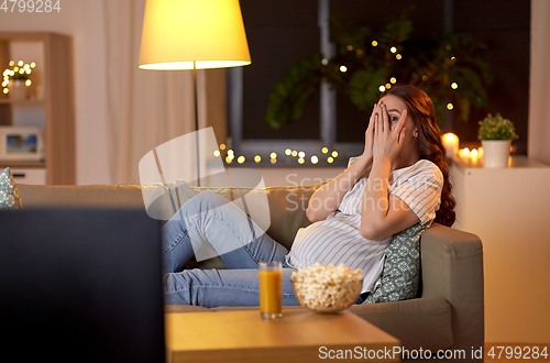 Image of scared pregnant woman watching tv at home