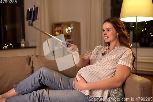 Image of happy smiling pregnant woman taking selfie at home