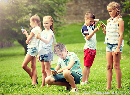 Image of kids with smartphones playing game in summer park