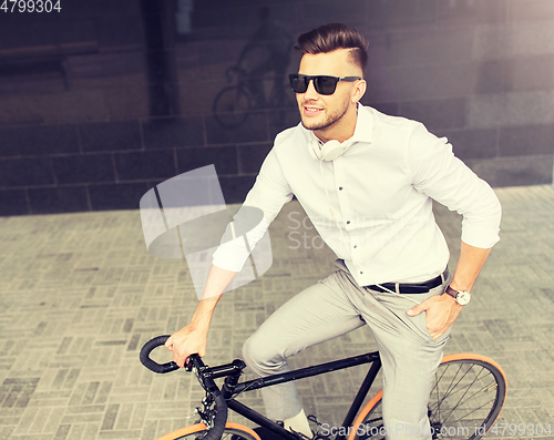 Image of man with bicycle and headphones on city street