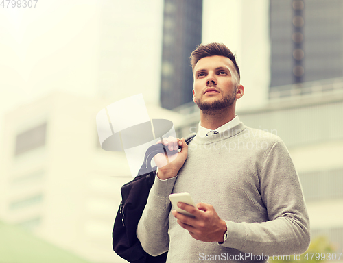 Image of young man with smartphone and bag in city