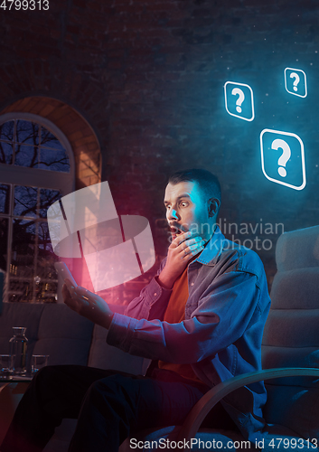 Image of Man using gadget and receive neon notifications at home at night