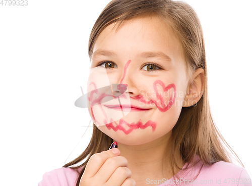 Image of Little girl is applying lipstick on her cheek