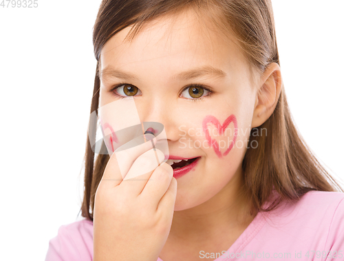 Image of Little girl is applying lipstick on her nose