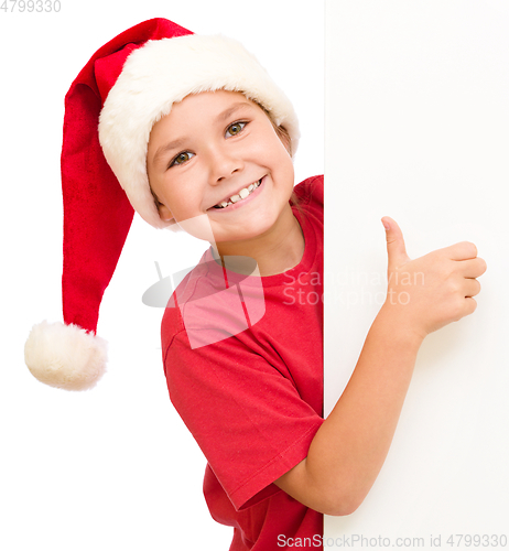 Image of Little girl in santa hat is holding blank board