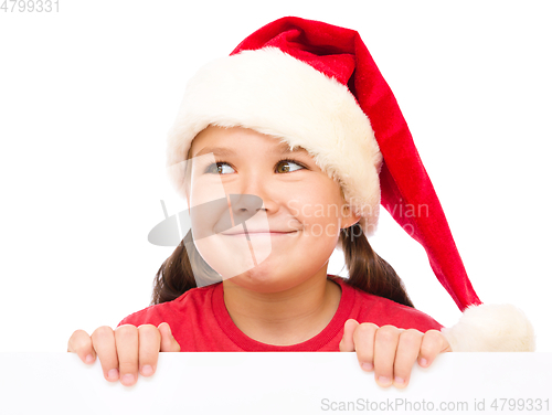 Image of Little girl in santa hat is holding blank board