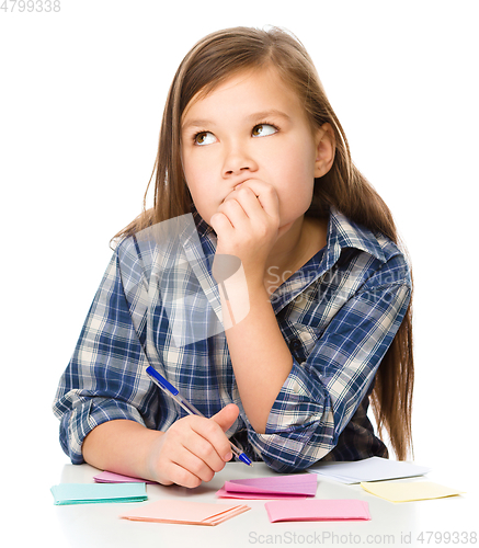 Image of Girl is writing on color stickers using pen