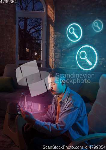 Image of Man using gadget and receive neon notifications at home at night