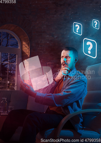 Image of Man using gadget and receive neon notifications at home at night