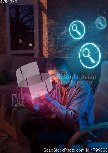 Image of Man using gadget and receive neon notifications at home at night