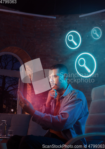 Image of Man using gadget and receive neon notifications at home at night