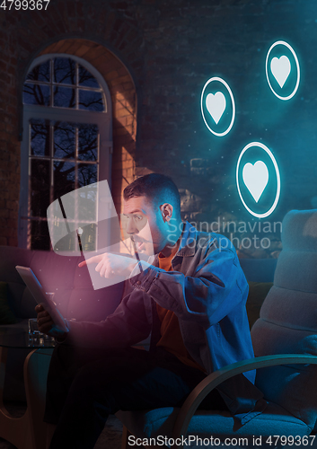 Image of Man using gadget and receive neon notifications at home at night