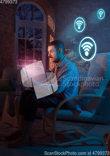 Image of Man using gadget and receive neon notifications at home at night
