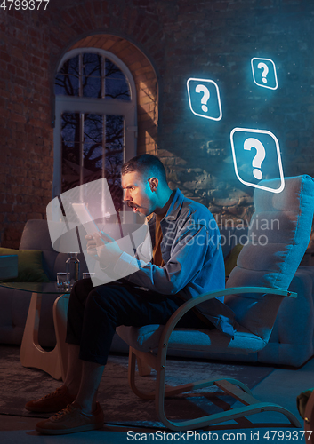 Image of Man using gadget and receive neon notifications at home at night