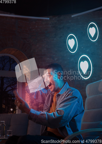 Image of Man using gadget and receive neon notifications at home at night