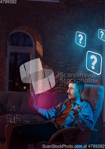 Image of Man using gadget and receive neon notifications at home at night