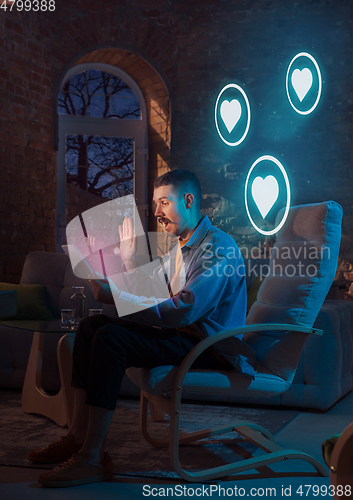 Image of Man using gadget and receive neon notifications at home at night