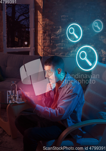 Image of Man using gadget and receive neon notifications at home at night