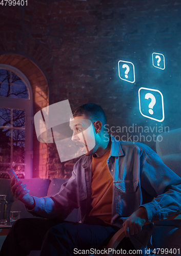 Image of Man using gadget and receive neon notifications at home at night