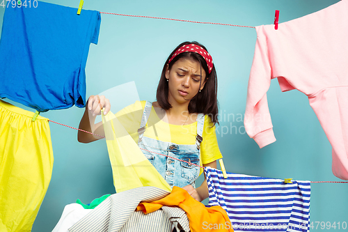 Image of Funny and beautiful housewife doing housework on blue background